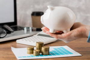 Imagem sobre recuperação financeira mostrando moedas e um cofre de porquinho de porcelana.